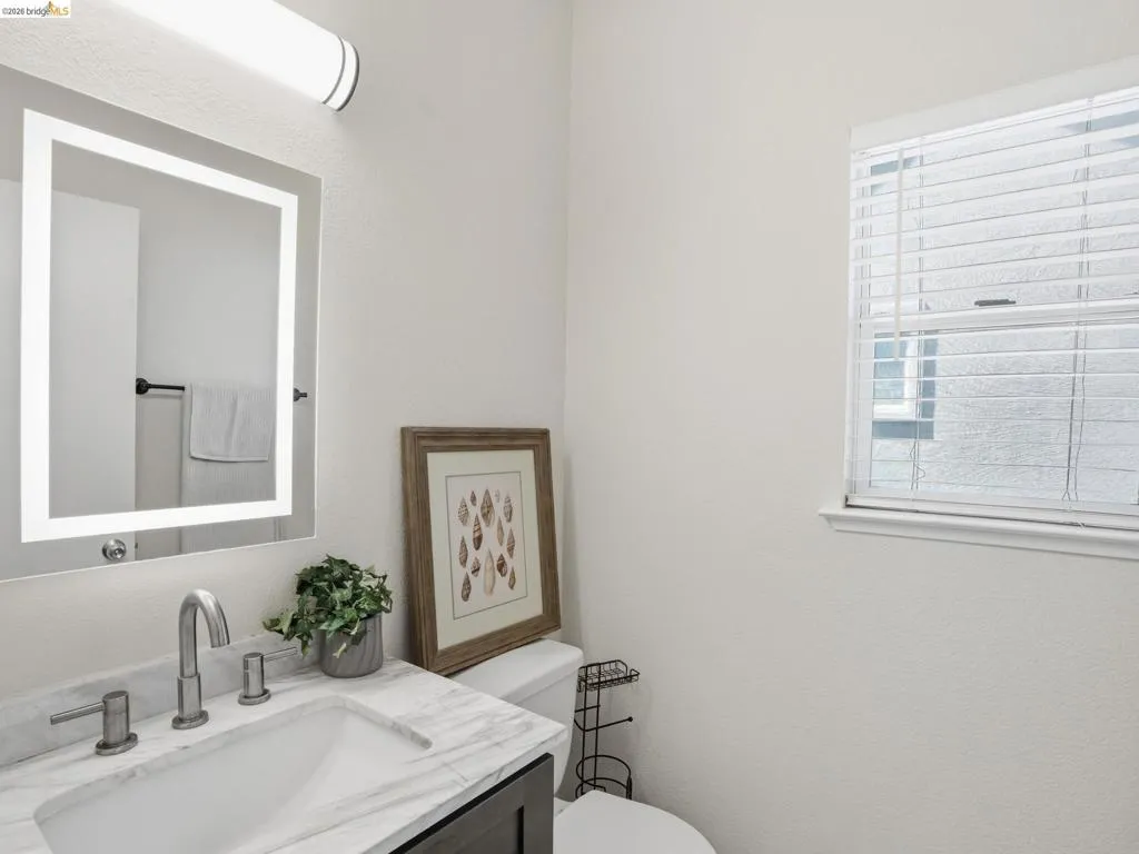Bathroom featuring a vanity with a rectangular undermount sink, a stone-finish countertop, and brushed nickel hardware