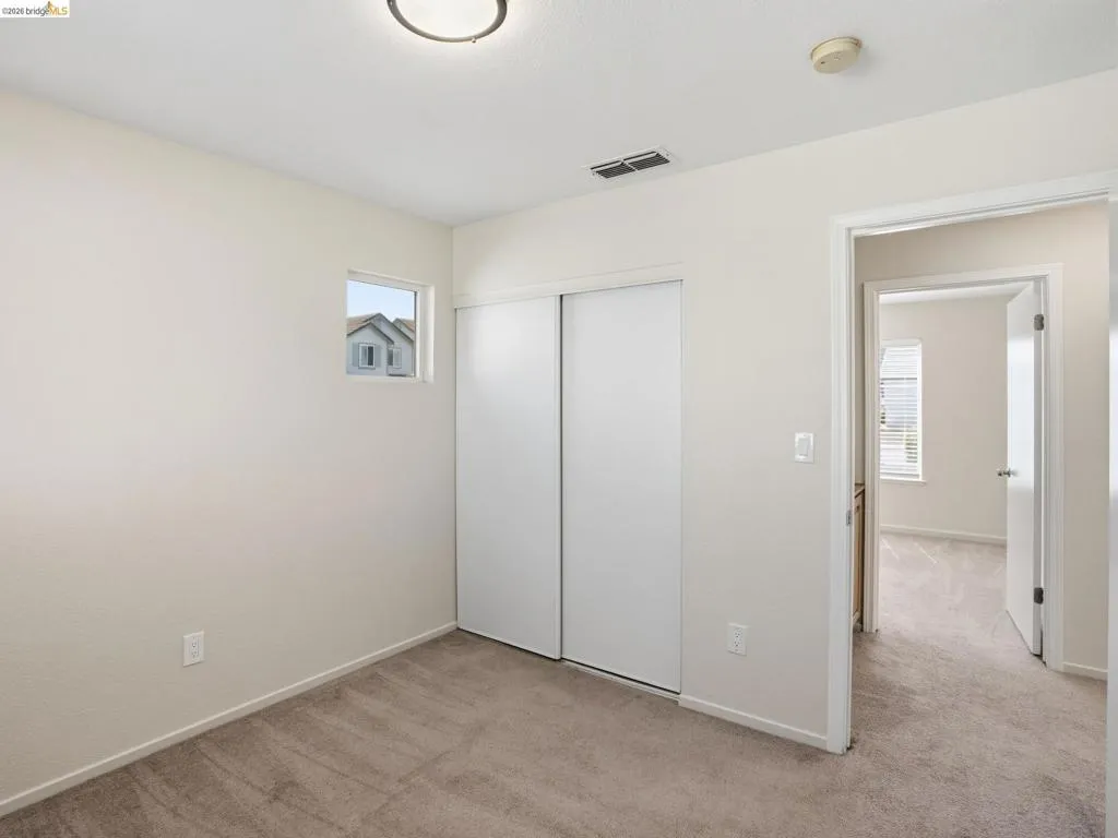 Carpeted room featuring a ceiling-mounted light fixture, a small window, and a white sliding closet door