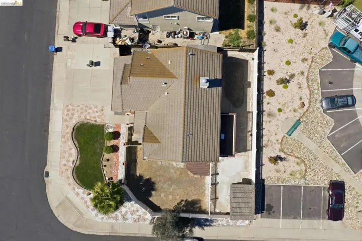 Corner lot property featuring a tiled roof, concrete driveway, and front landscaping with manicured lawn and decorative stones
