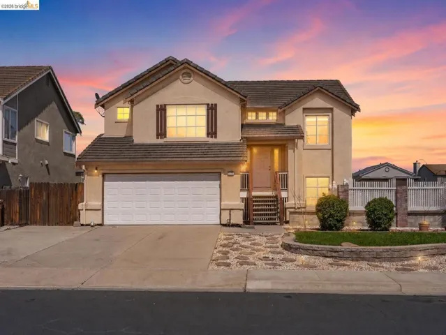 Two-story stucco residence featuring a tile roof and decorative window shutters