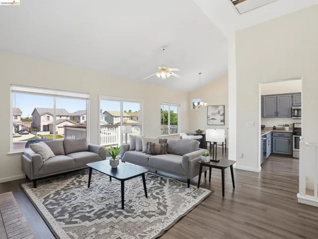 Spacious living area featuring vaulted ceilings, wood-finish flooring, and multiple windows