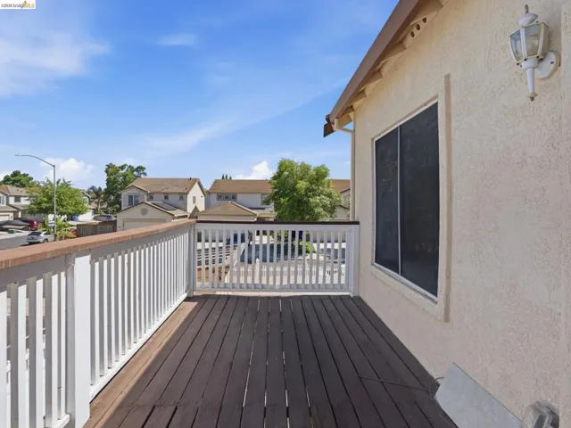 Private balcony featuring composite wood-finish decking and white wood railing