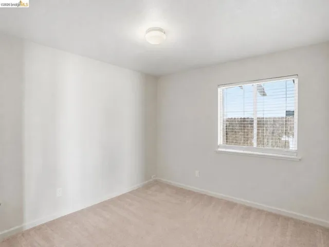Carpeted room featuring a single window with blinds, a ceiling-mounted light fixture, and neutral wall paint