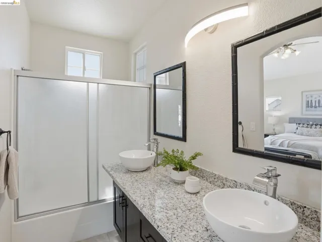 Dual vessel sinks set on a speckled countertop with dark cabinetry