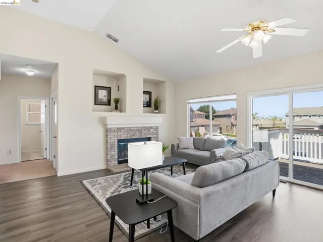 Living area featuring vaulted ceilings, wood-finish flooring, and a stone-surround fireplace with built-in display niches