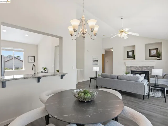 Open-concept living space featuring vaulted ceilings, a contemporary chandelier, and wood-finish flooring