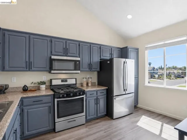 Kitchen featuring abundant blue cabinetry, stainless steel appliances, speckled countertops, and wood-finish flooring
