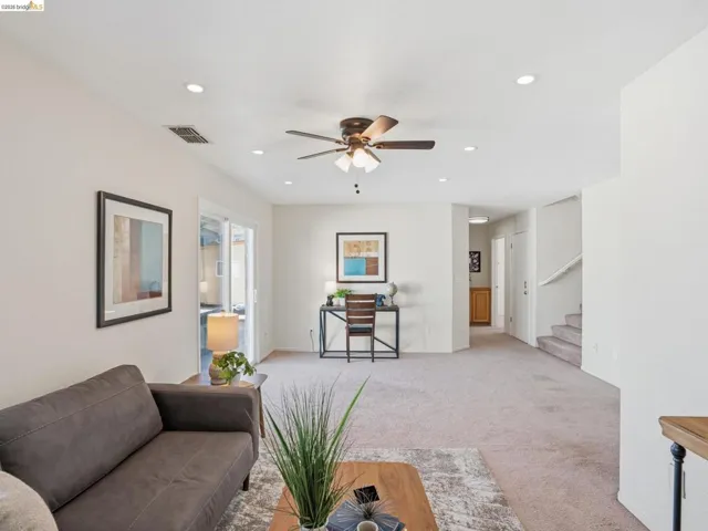 Open-concept living area with neutral carpeting and light wall tones