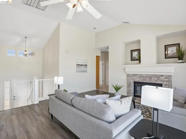 Vaulted ceiling living space featuring wood-finish flooring and an integrated brick-surround fireplace