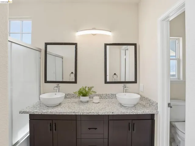 Double vanity featuring granite-look countertops, vessel sinks, and dark wood-finish cabinetry