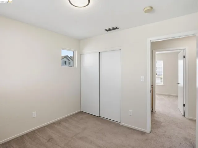 Carpeted room featuring a ceiling-mounted light fixture, a small window, and a white sliding closet door