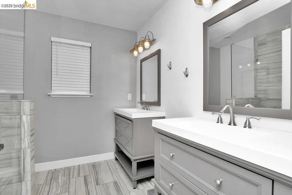Dual vanity bathroom featuring gray cabinetry, white countertops, and brushed nickel fixtures