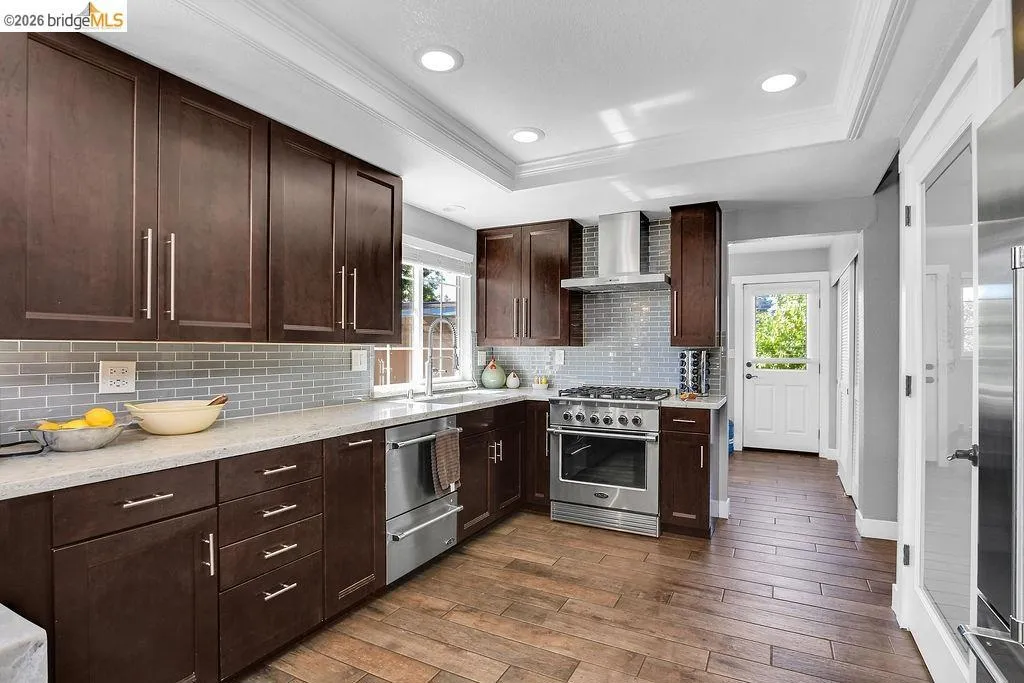 Kitchen featuring rich wood-finish cabinetry, light-toned countertops, and a full tile backsplash