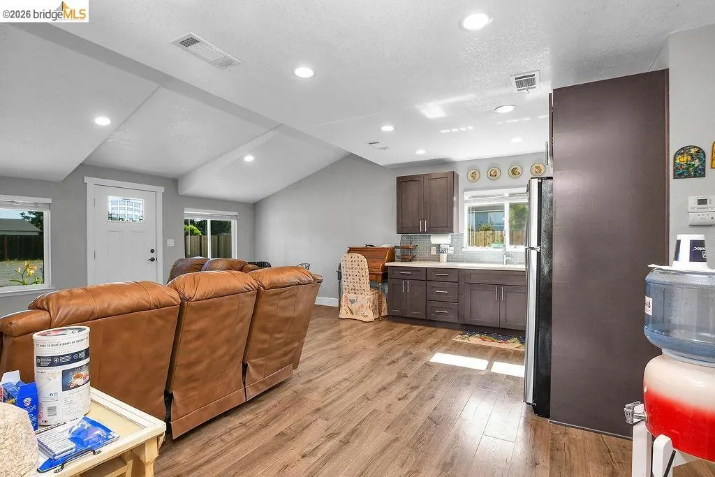 Open-concept living space featuring wood-finish flooring, recessed lighting, and a vaulted ceiling