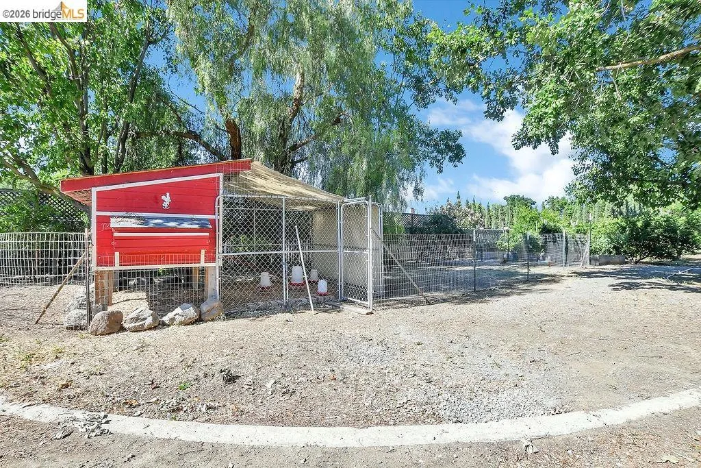 Red coop with white trim, featuring a rooster emblem and an attached fenced enclosure