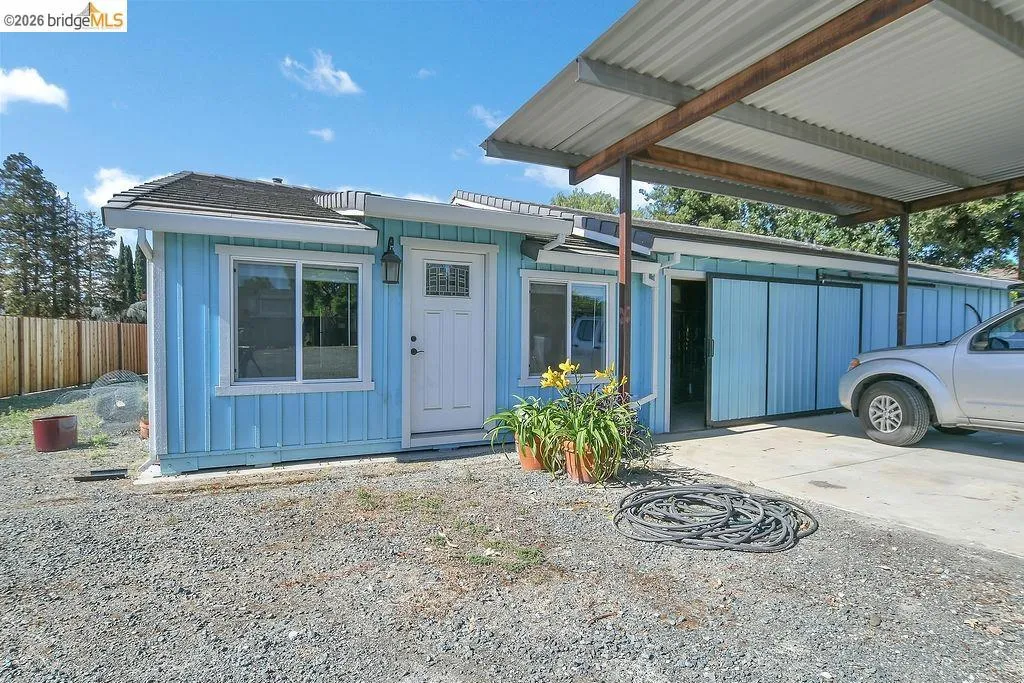 Blue exterior with white trim, featuring a partial gravel and paved driveway
