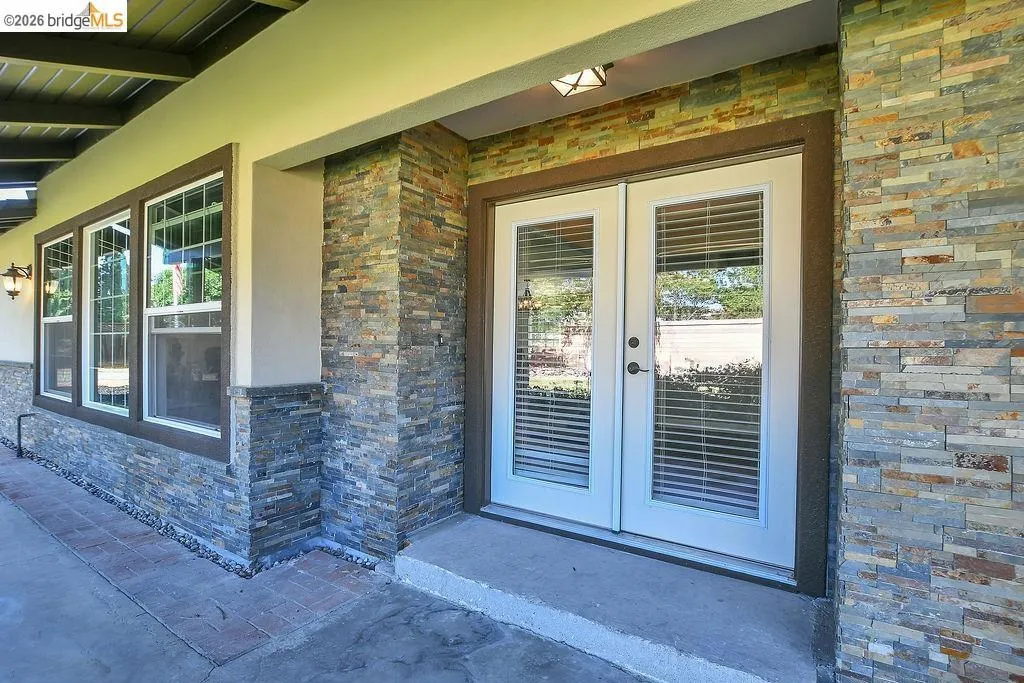 Dual French doors with integrated blinds, framed by stacked stone veneer