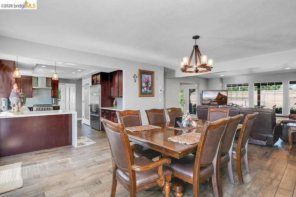 Dining area with wood-finish flooring, a wood-frame chandelier, and a wood dining table