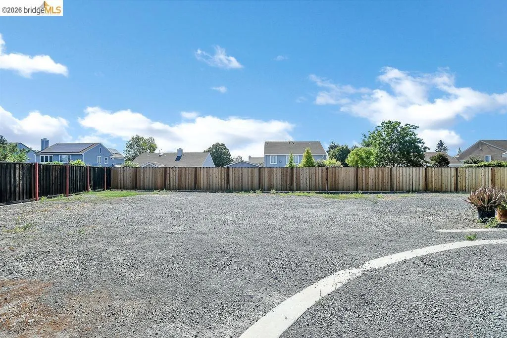 Expansive gravel yard with perimeter wood fencing