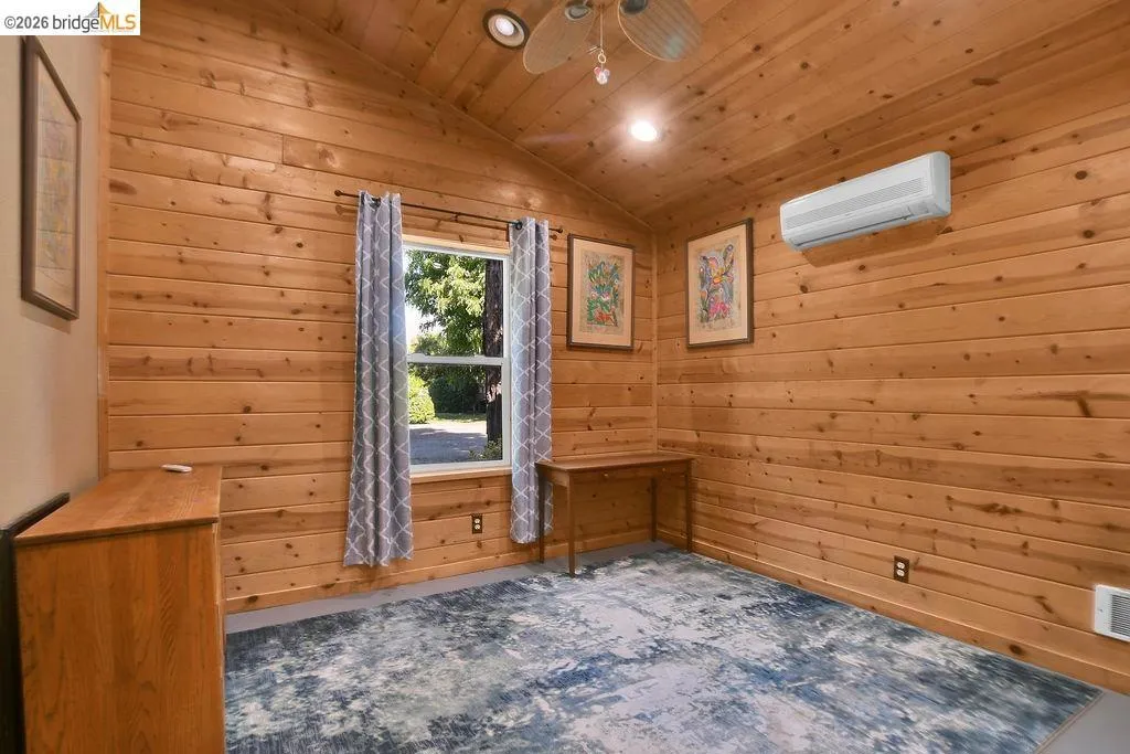 Room featuring wood-plank walls and ceiling, a vaulted ceiling, a window with exterior visibility, recessed lighting, and a wall-mounted mini-split unit