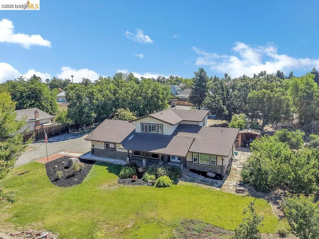 Expansive residence with multiple rooflines and a neutral exterior palette, set on a verdant lot