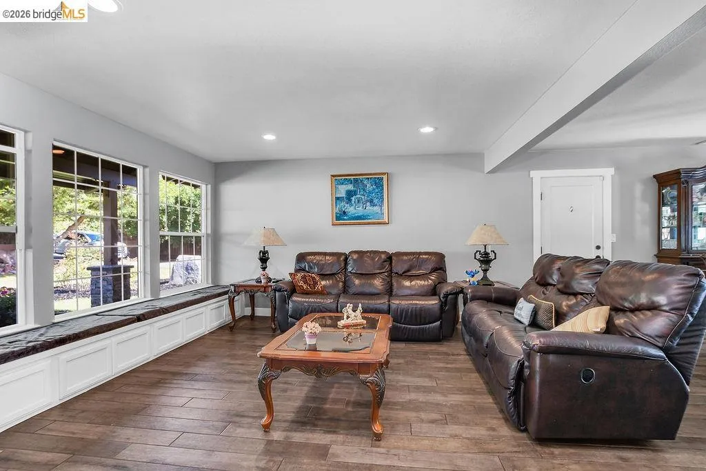 Room featuring wood-finish flooring, recessed lighting, and a window seat with white paneled storage