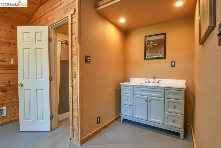 Vanity area featuring a light grey cabinet with multiple drawers and double doors, a white countertop, and a chrome faucet set