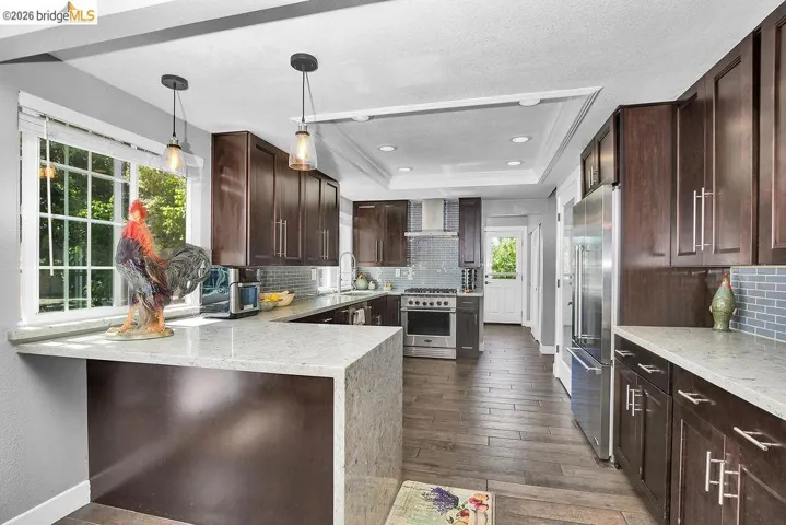Kitchen featuring extensive dark wood cabinetry, light-toned countertops, and a tiled backsplash