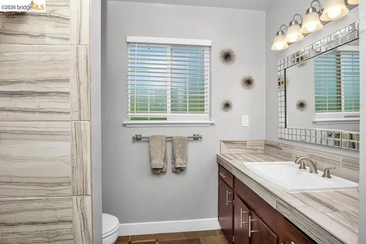 Bathroom vanity featuring a single basin, brushed nickel faucet, and a decorative tile-framed mirror
