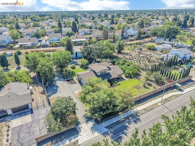 Expansive residential property featuring a multi-level home with a brown shingle roof, mature perimeter trees, and a spacious front yard
