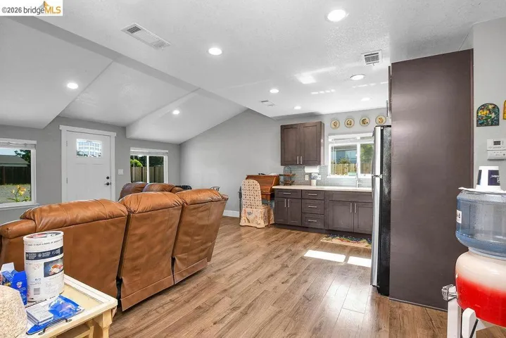 Open-concept living space featuring wood-finish flooring, recessed lighting, and a vaulted ceiling