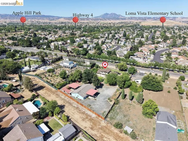 Expansive aerial view of a residential area featuring numerous single-family homes with pitched roofs, mature trees, and visible street infrastructure
