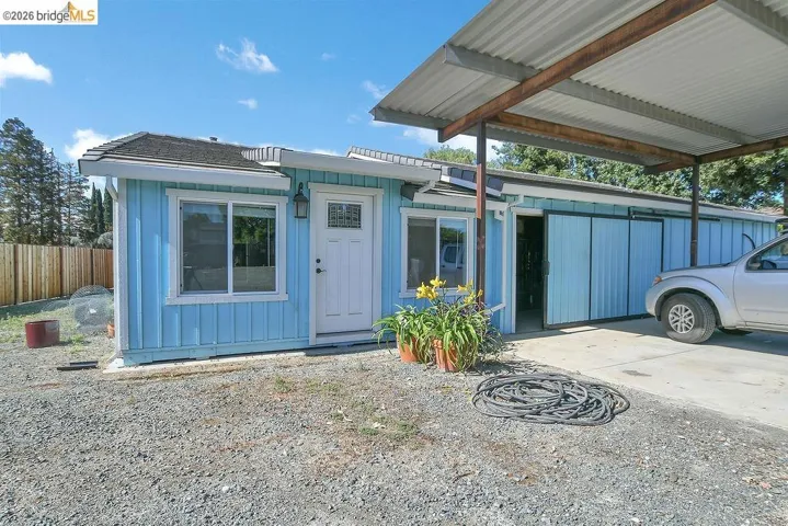 Blue exterior with white trim, featuring a partial gravel and paved driveway