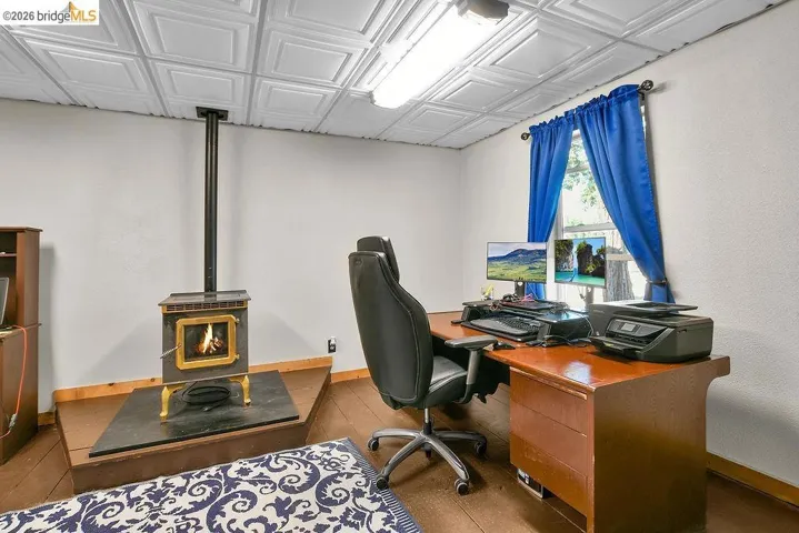 Room featuring a freestanding wood-burning stove with a hearth, wood-finish flooring, and a decorative ceiling