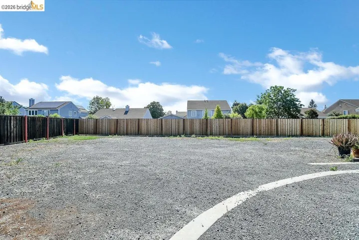 Expansive gravel yard with perimeter wood fencing