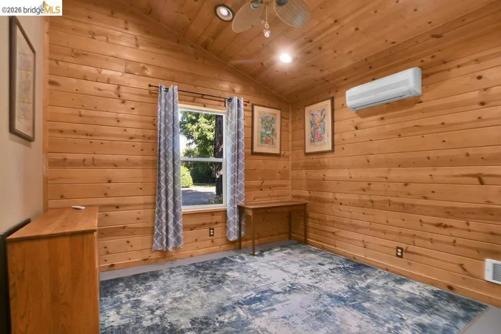 Room featuring wood-plank walls and ceiling, a vaulted ceiling, a window with exterior visibility, recessed lighting, and a wall-mounted mini-split unit