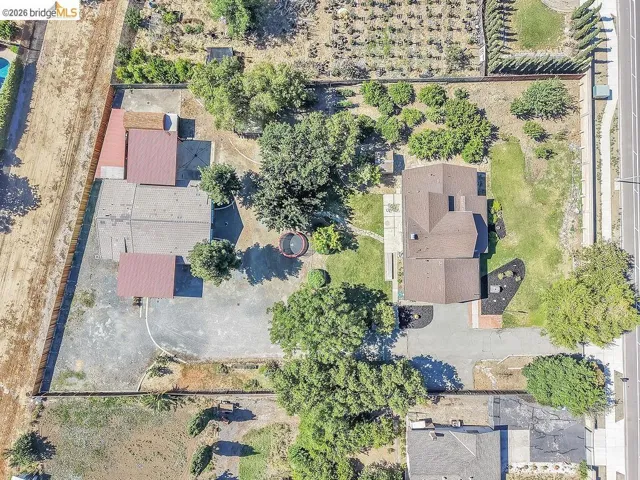 Expansive property featuring a main residence with a brown shingle roof, surrounded by mature trees and landscaped areas