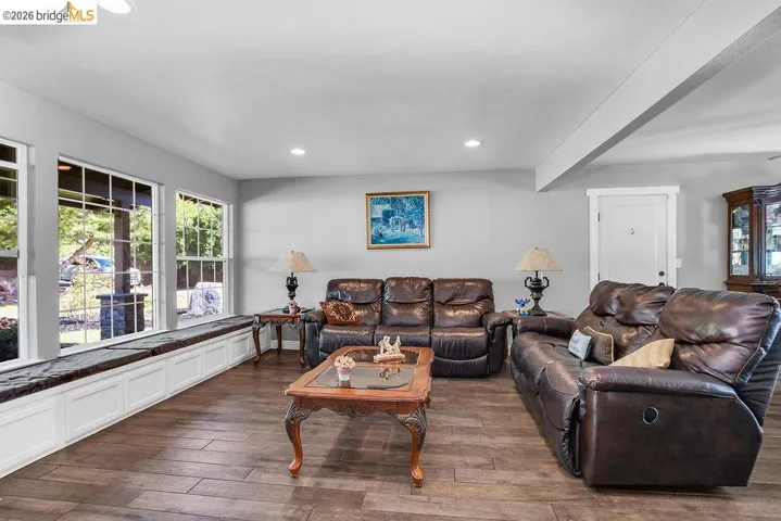 Room featuring wood-finish flooring, recessed lighting, and a window seat with white paneled storage