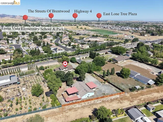 Aerial perspective showcasing the property's expansive lot, mature trees, and surrounding neighborhood