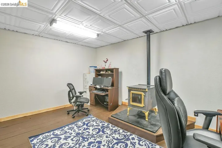 Room featuring a freestanding stove on a raised hearth with a metal flue