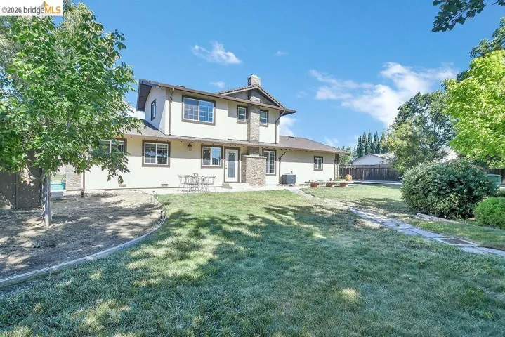 Spacious backyard with a two-story stucco exterior, stone accents, and a stone walkway