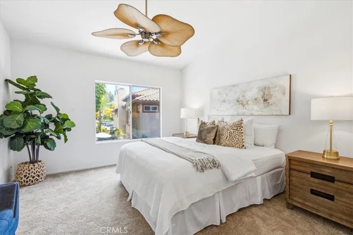 Primary bedroom featuring natural light, neutral tones, and modern ceiling fan.