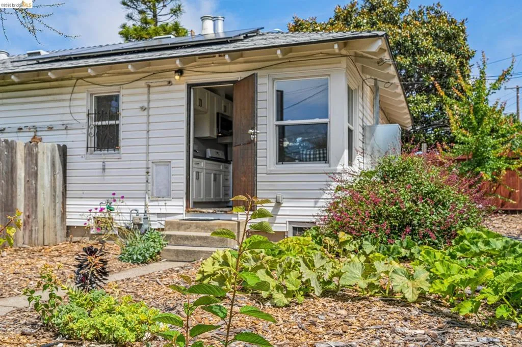 White siding exterior with a wood-finish entry door
