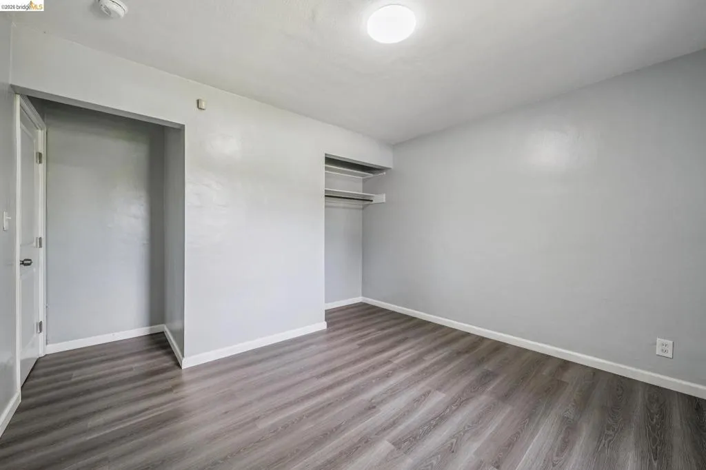Room featuring wood-finish flooring, light gray wall paint, and white trim