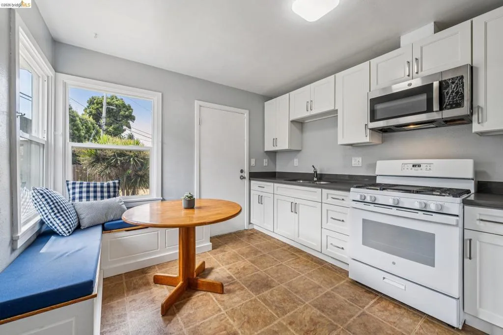 Kitchen featuring white cabinetry, dark countertops, tile flooring, and a built-in window bench