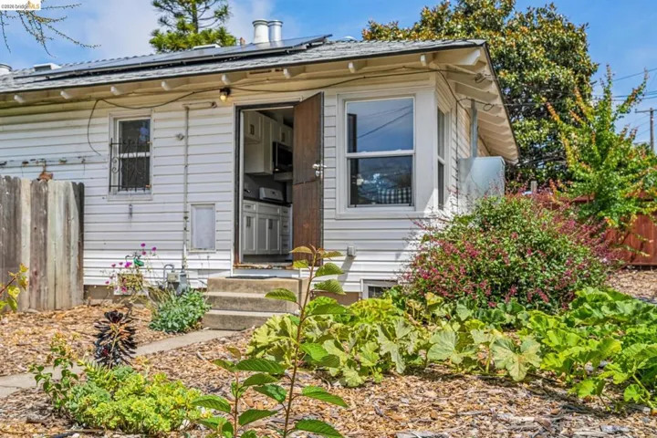 White siding exterior with a wood-finish entry door