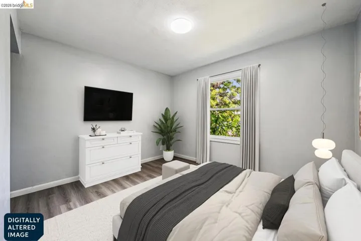 Spacious room featuring wood-finish flooring, a large window with natural light, modern ceiling light fixture, and light gray wall tones
