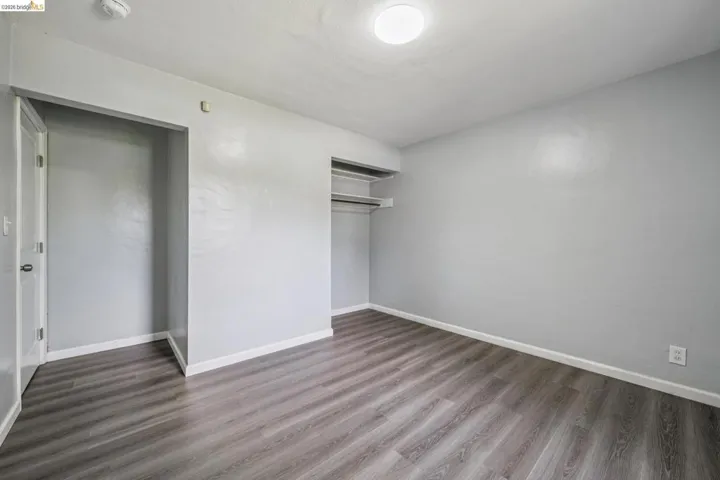 Room featuring wood-finish flooring, light gray wall paint, and white trim