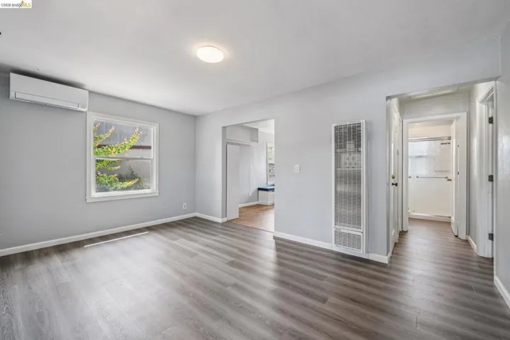 Spacious room featuring wood-finish flooring, light gray wall paint, and a white ceiling with a flush-mount light fixture