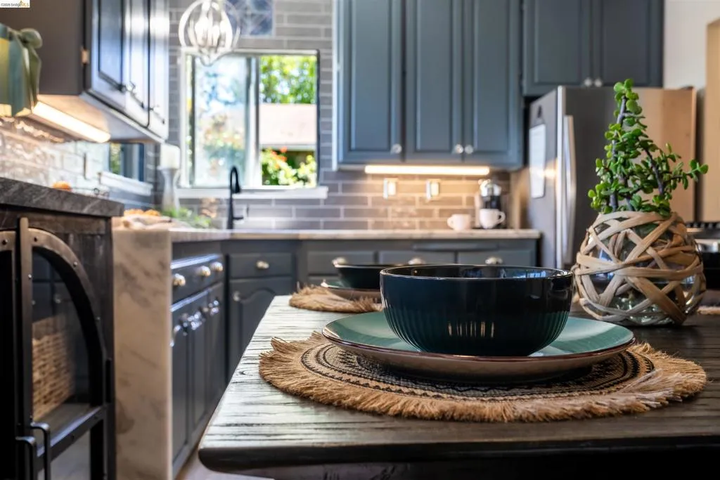 Kitchen featuring painted cabinetry with brushed nickel hardware, a subway tile backsplash, under-cabinet lighting, and a stainless steel refrigerator